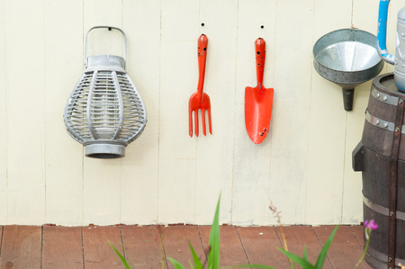 Garden tools hanging and watering can on shed door with vintage feelの写真素材