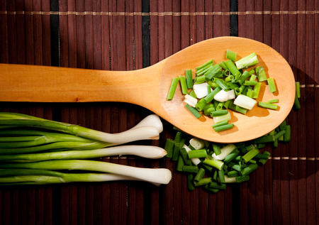 Chopped green  onions and spoon on a wooden