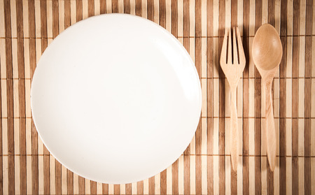 wooden spoon and fork and empty dish display on bamboo naperyの写真素材