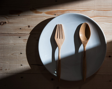 plate with fork and spoon on wood ,with shadowsの写真素材