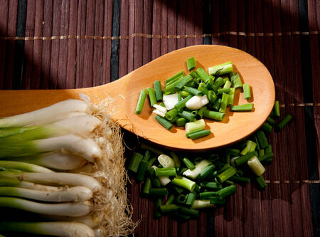 Chopped green  onions and spoon on a woodenの写真素材