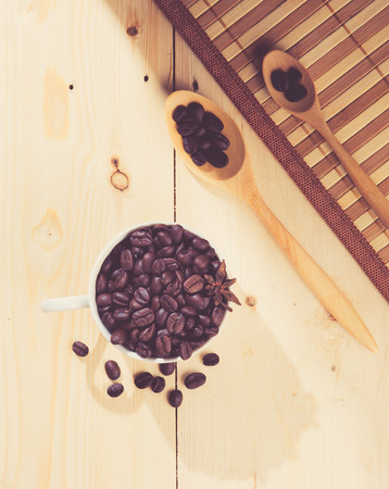 Coffee beans in cup on wood background,selective focus, retro filter effectの写真素材