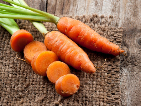 Fresh carrot with green leaves on jute bagの写真素材