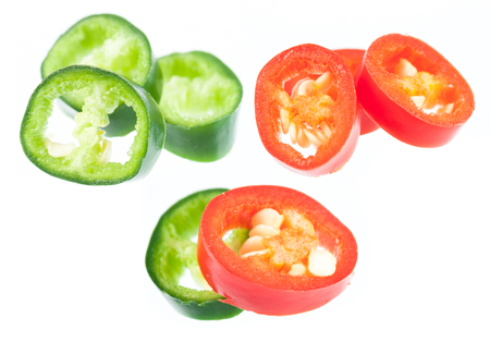 Sliced in pieces red and green chili peppers isolated over white backgroundの写真素材