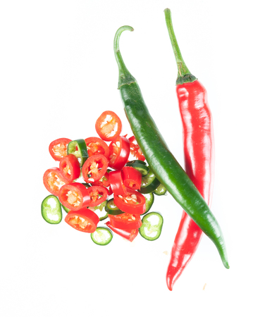 Sliced in pieces red and green chili peppers isolated over white backgroundの写真素材