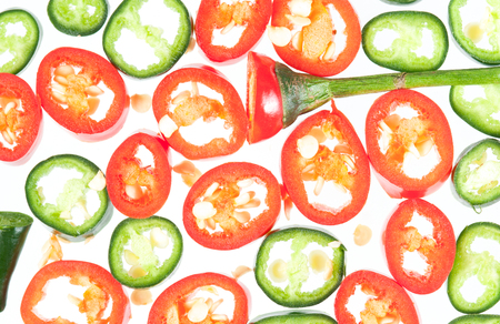 Sliced in pieces red and green chili peppers isolated over white backgroundの写真素材
