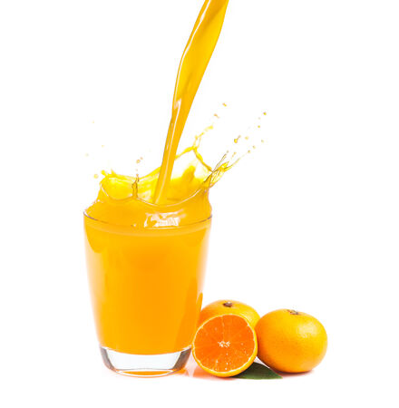 splashing orange juice with oranges against white の写真素材