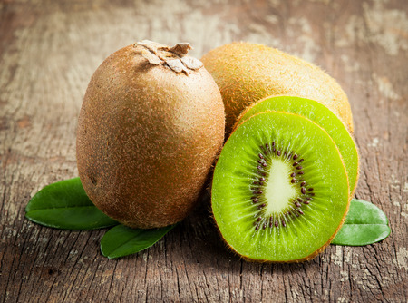 Fresh Whole kiwi fruit and his sliced half on wooden の写真素材