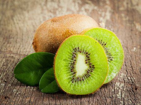 Fresh Whole kiwi fruit and his sliced half on wooden の写真素材