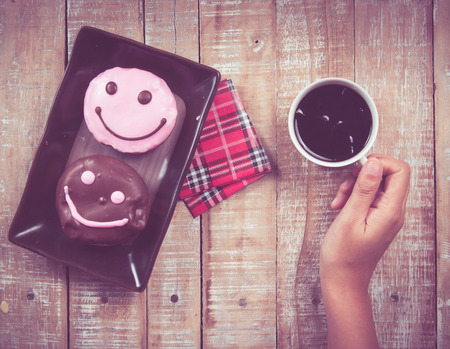 donuts and coffee on the wood background,vintage color toned imageの写真素材