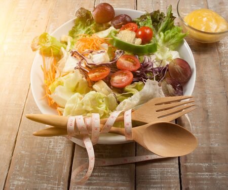 Fresh healthy salad, utensil and measure tape on wooden background,View from aboveの写真素材