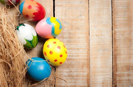 Easter eggs and hay on wooden background