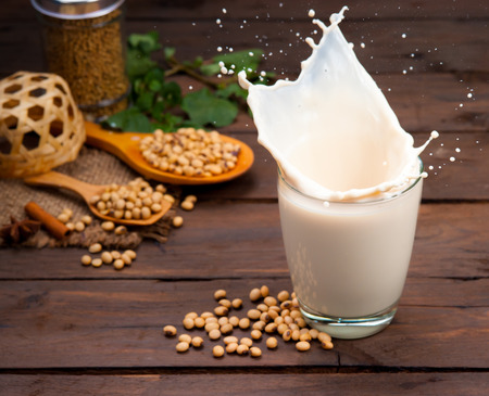Soy milk splash with beans on woodの写真素材