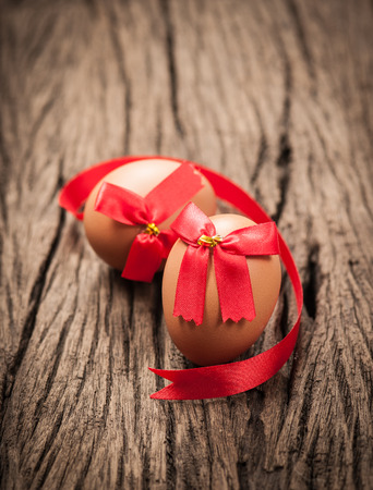 easter eggs wrapped around red ribbon bow on woodの写真素材