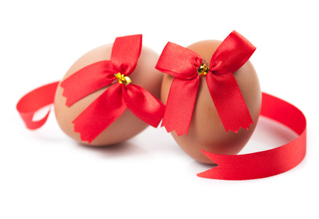 easter eggs wrapped around red ribbon bow over white backgroundの写真素材