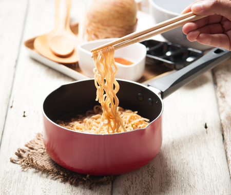 Instant noodles in frying pan on woodの写真素材