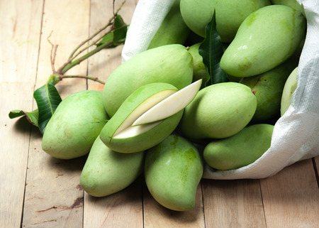 Fresh green mango with white plastic sack on woodの写真素材