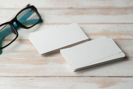 blank business cards and eyeglasses on wooden tableの写真素材