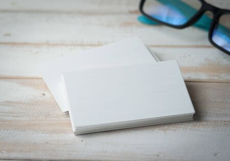 blank business cards and eyeglasses on wooden tableの写真素材