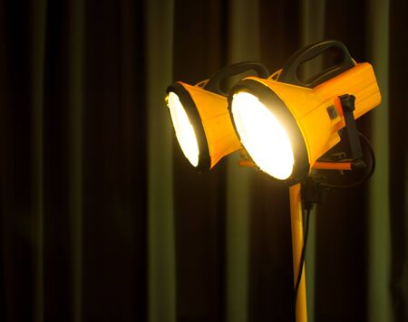 Halogen work lights on yellow tripod,dark background