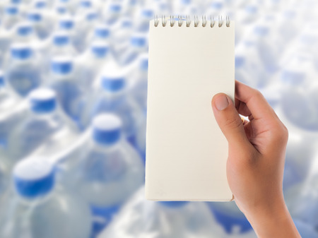 Hand hold blank notepad with space for text,Blur water bottles backgroundの写真素材