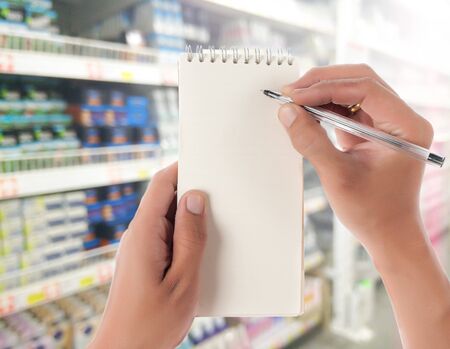 Hand hold blank notepad with space for text,Supermarket blur background
