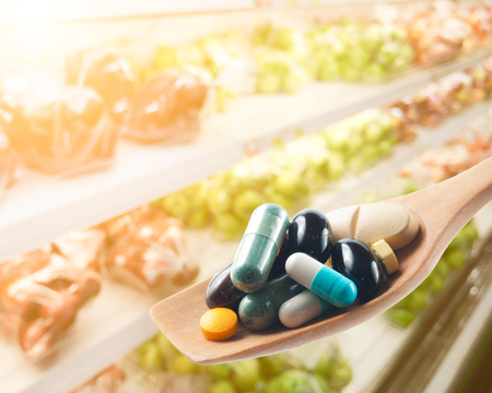Various drugs vitamins and nutrition supplements on spoon,Blur fruits backgroundの写真素材