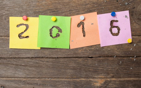 New year 2016 of burned in papernote on a wooden background