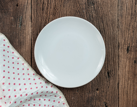 Empty white plate at classic checkered tablecloth on wooden tableの写真素材