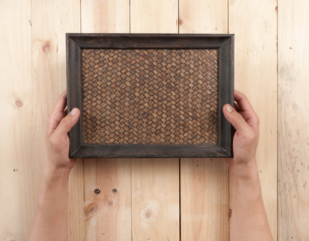 Hand hold a wooden tray on table wood, top view