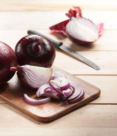 Red onion and cutting board on wooden table, selective focusの写真素材