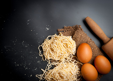 Yellow noodles drying with eggs on blackboard backgroundの写真素材