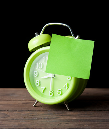 Green alarm clock and sticky paper with Text Space isolated on dark backgroundの写真素材