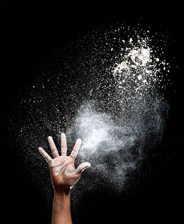 Hand and flour on black backgroundの写真素材