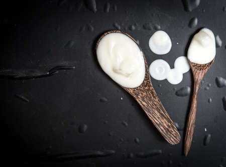 Wooden spoon with milk cream on a black slate
