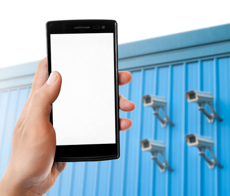 Hand holding smart phone on blurred CCTV camera background. Security online concept.
