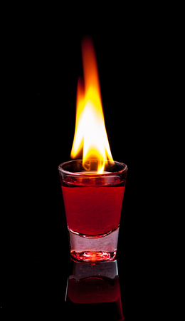 Burning Red cocktail in shot glass on black background