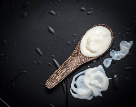 Wooden spoon with milk cream on a black slateの写真素材