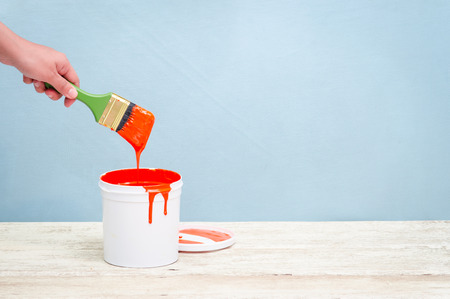 Hand holding the paint brush and White plastic bucket with red color on wood,vintage backgroundの写真素材