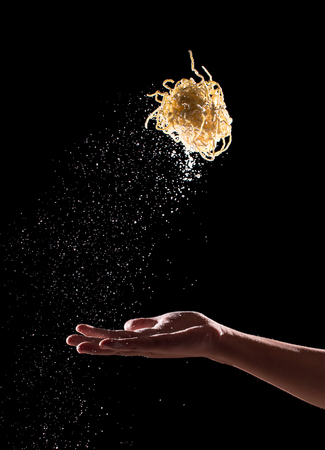 Hand throwing egg noodles on dark background,Flying egg noodlesの写真素材