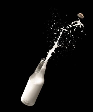 Milk bottle and splashes isolated on black backgroundの写真素材