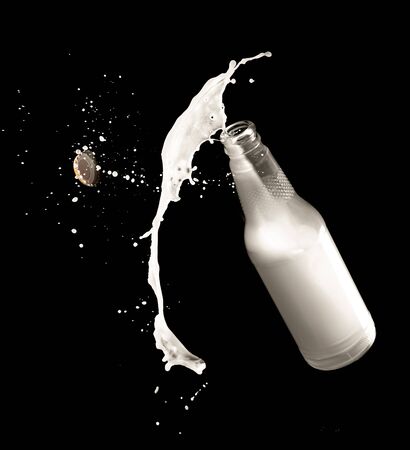 Milk bottle and splashes isolated on black backgroundの写真素材