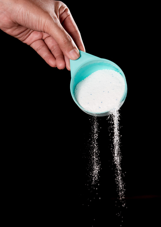 Pouring washing powder over black background.の写真素材