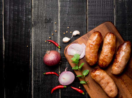Fried sausages with herbs on black wood,top view