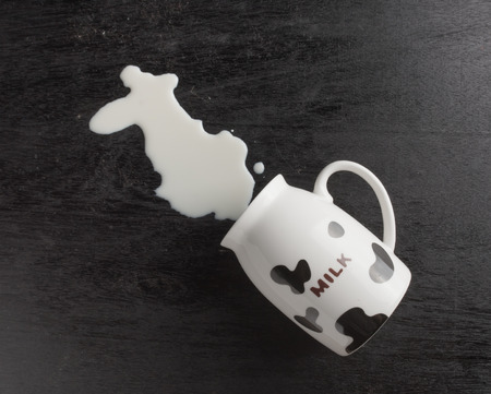 Milk spilled from glass on dark woodenの写真素材
