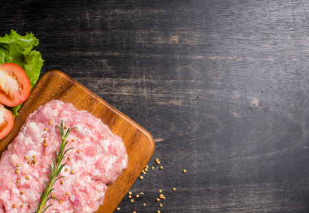 Minced pork uncooked with cutting board on wood background, top viewの写真素材