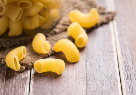 Raw macaroni on wooden background