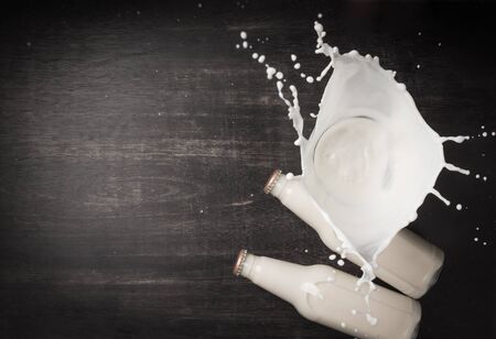 Milk splash and bottle milk on dark wooden table,Top viewの写真素材