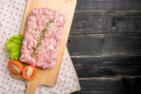 Minced pork uncooked with cutting board on wood background, top viewの写真素材