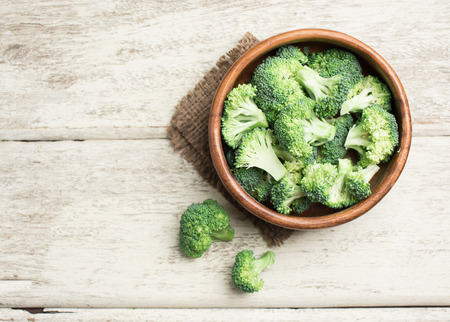 Broccoli in wood bowl over rustic wooden background,healthy or vegetarian food concept,top viewの写真素材
